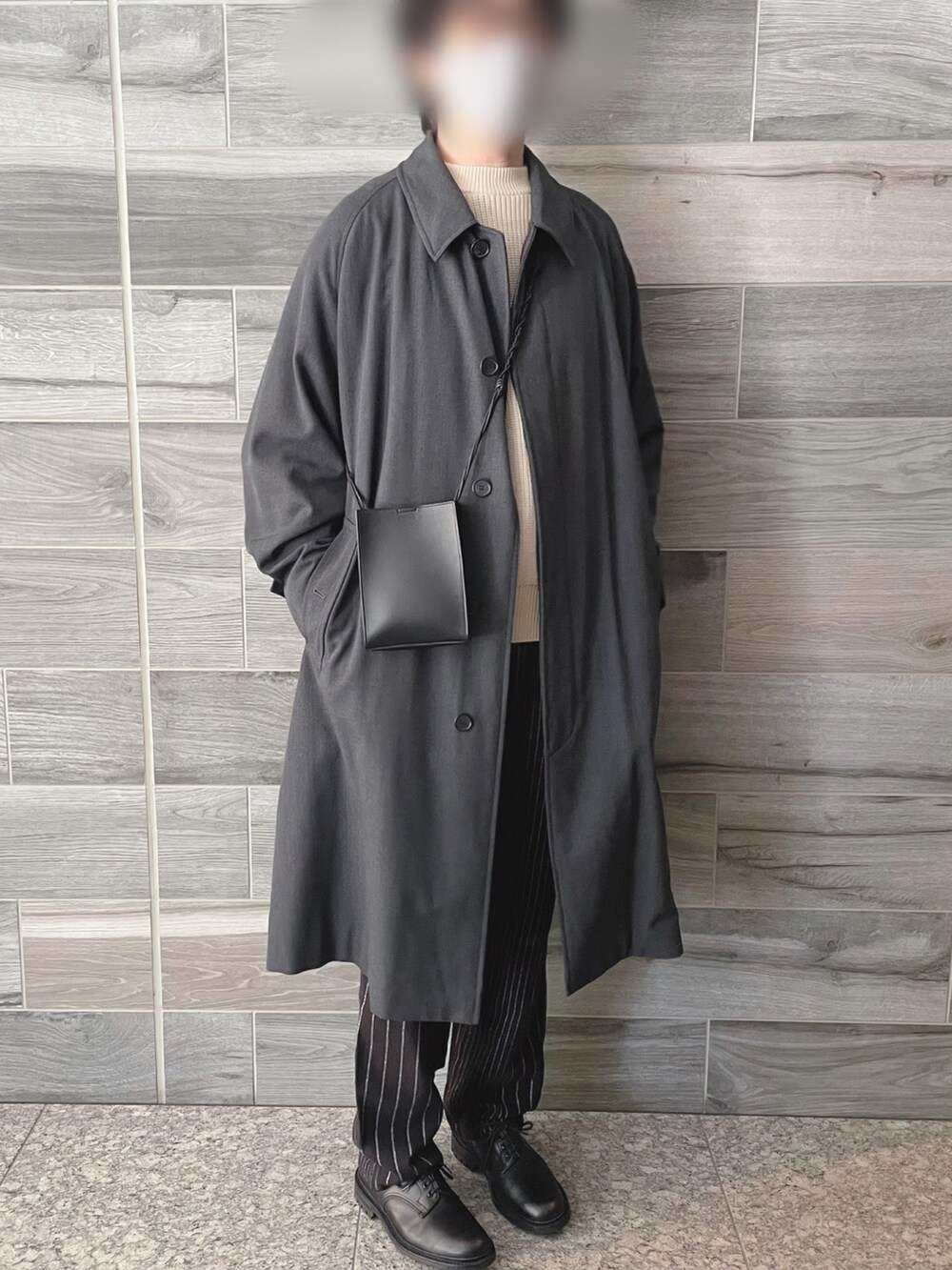 グレー系のステンカラーコート、ホワイト系のニット/セーター、ブラック系のスラックスを着用したメンズの冬コーディネートの2枚目の写真