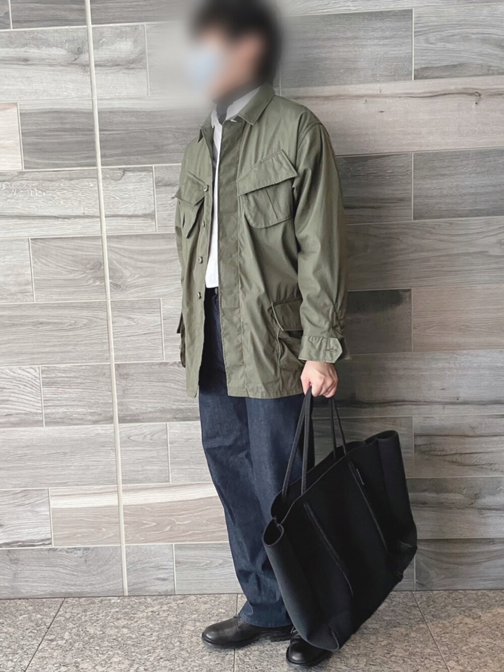 グリーン系のミリタリージャケット、ホワイト系のシャツ/ブラウス、ブラック系のニット/セーターを着用したメンズの春コーディネートの2枚目の写真