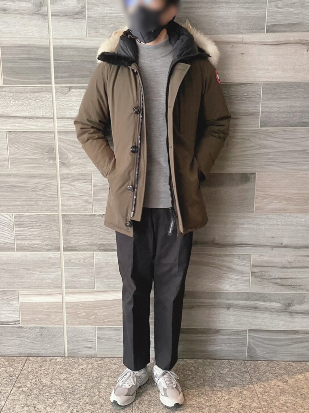 グリーン系のダウンジャケット/コート、ブラック系のスラックス、グレー系のニット/セーターを着用したメンズの冬コーディネートの2枚目の写真