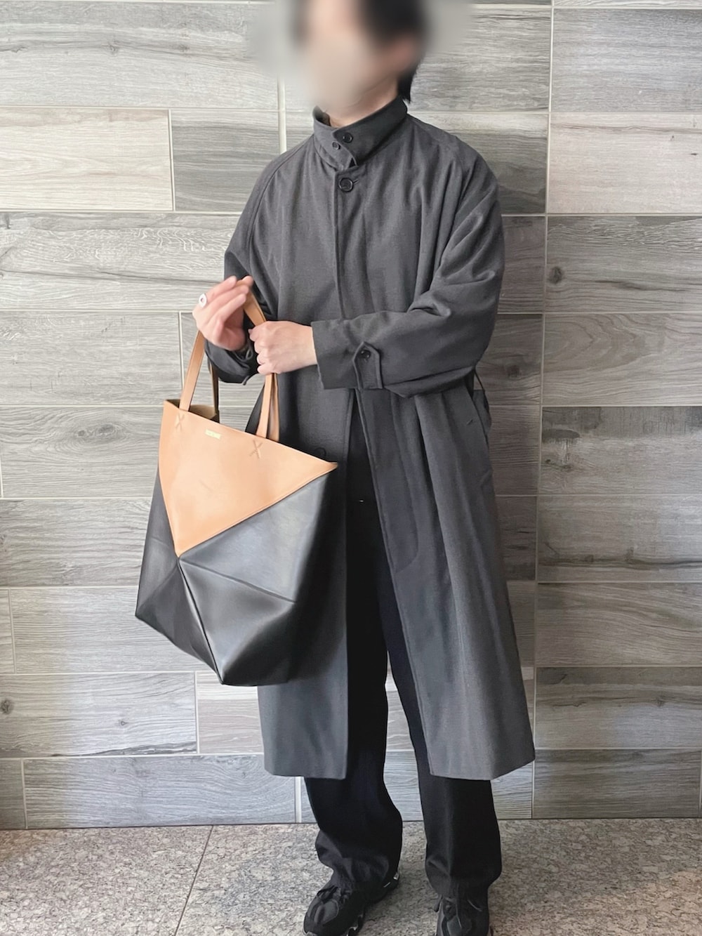 グレー系のステンカラーコート、ブラック系のデニムパンツ、ブラック系のスウェットを着用したメンズの春コーディネートの3枚目の写真