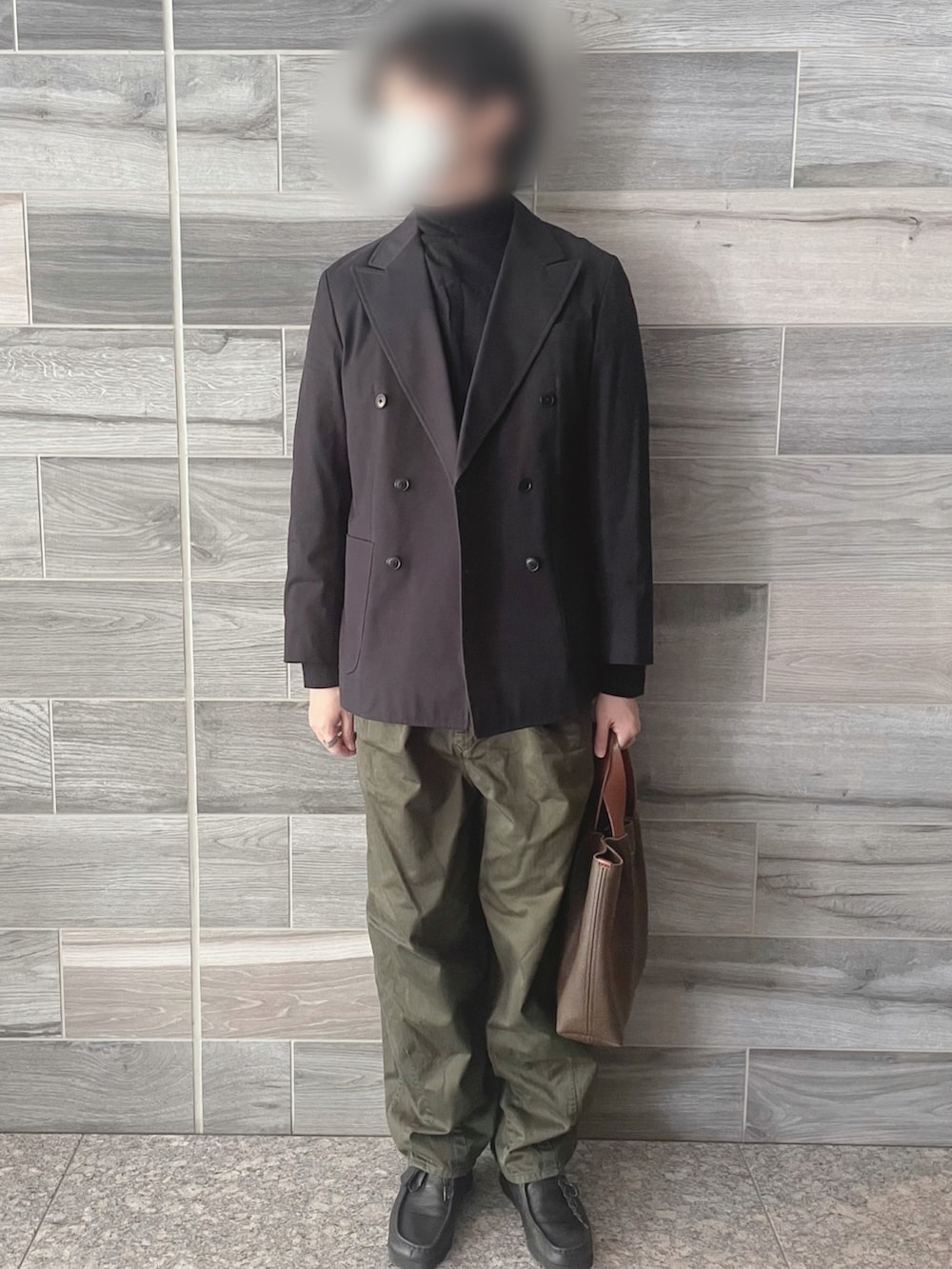 ブラック系のテーラードジャケット、ブラック系のニット/セーター、グリーン系のパンツを着用したメンズの秋コーディネートの3枚目の写真