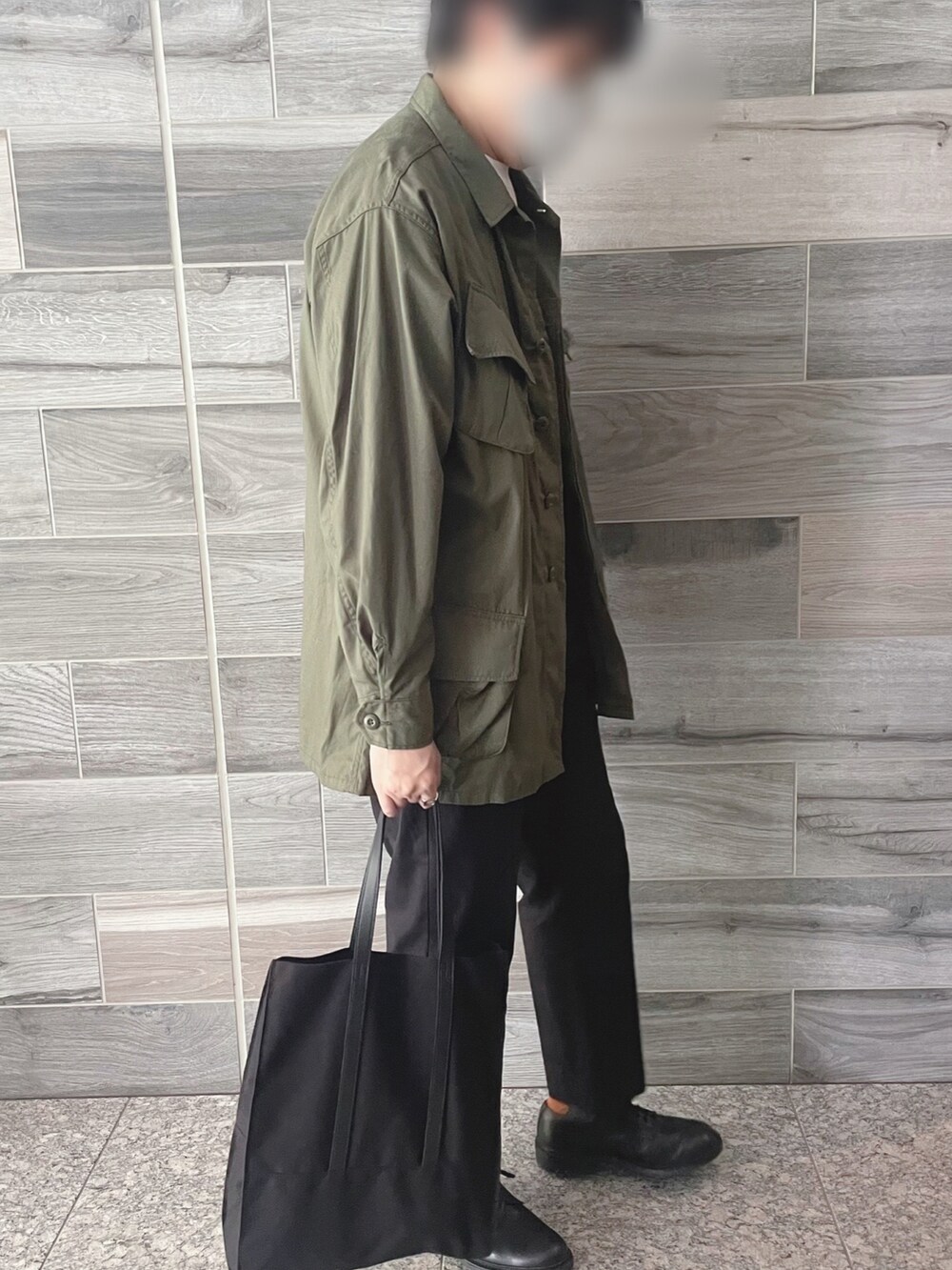 グリーン系のミリタリージャケット、ブラック系のスラックス、ブラック系のシューズを着用したメンズの秋コーディネートの3枚目の写真