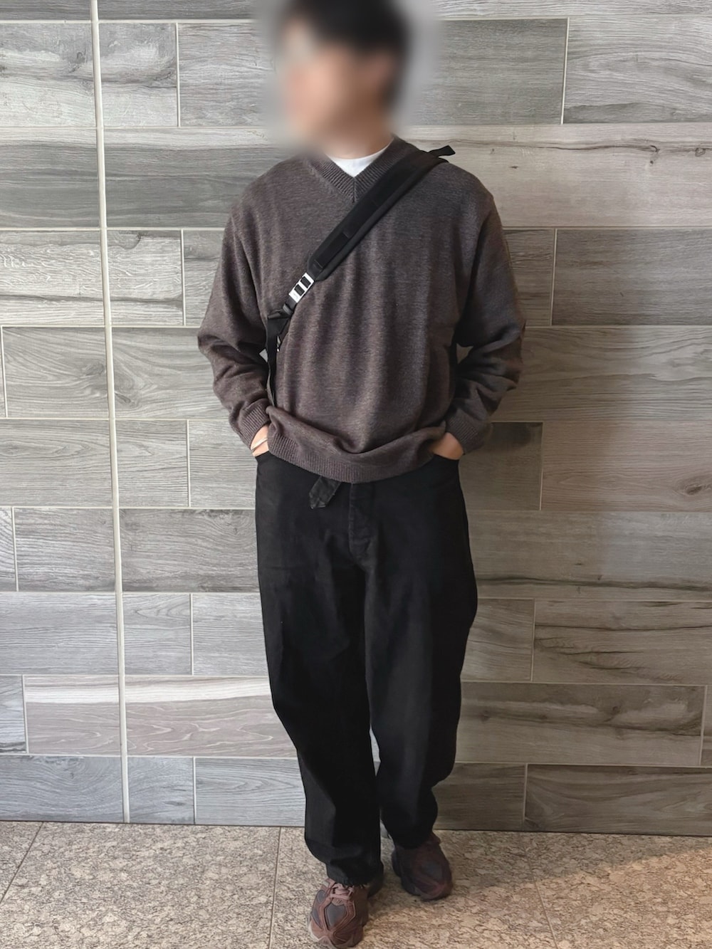 グレー系のニット/セーター、ブラック系のデニムパンツ、ブラウン系のスニーカーを着用したメンズの秋コーディネートの2枚目の写真