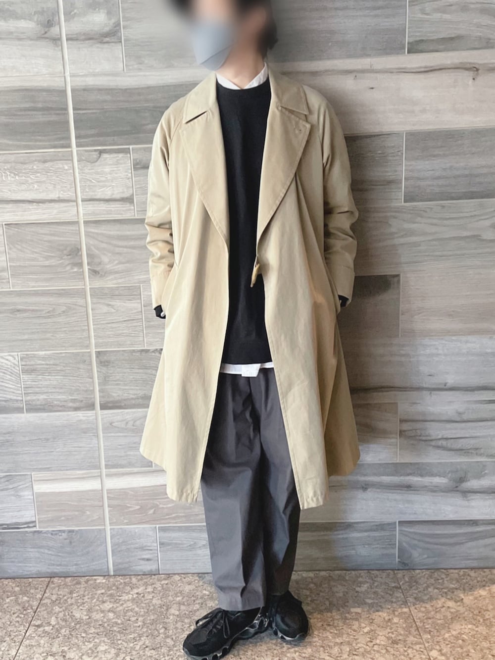 ベージュ系のトレンチコート、ブラック系のスウェット、グレー系のパンツを着用したメンズの冬コーディネートの2枚目の写真