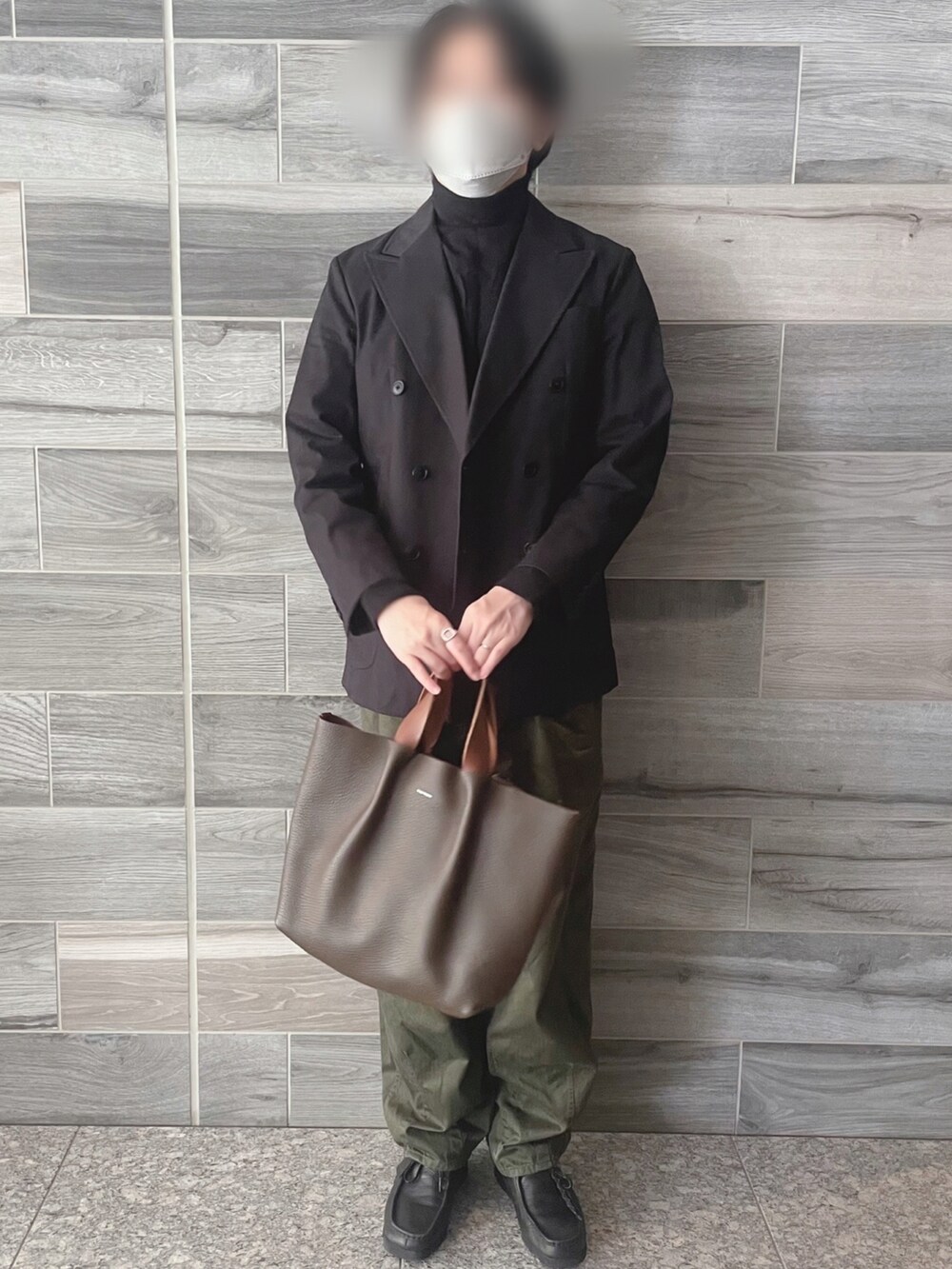 ブラック系のテーラードジャケット、ブラック系のニット/セーター、グリーン系のパンツを着用したメンズの秋コーディネートの2枚目の写真