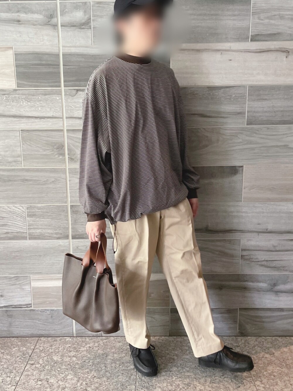 ブラック系のTシャツ/カットソー、ベージュ系のチノパンツ、ブラウン系のトートバッグを着用したメンズの秋コーディネートの2枚目の写真