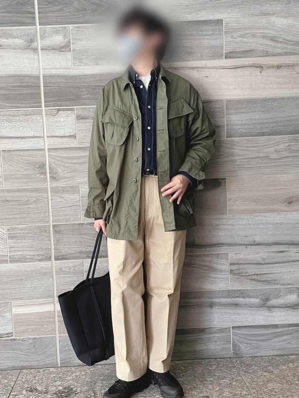 グリーン系のミリタリージャケット、ブルー系のシャツ/ブラウス、ベージュ系のチノパンツを着用したメンズの春コーディネートの3枚目の写真