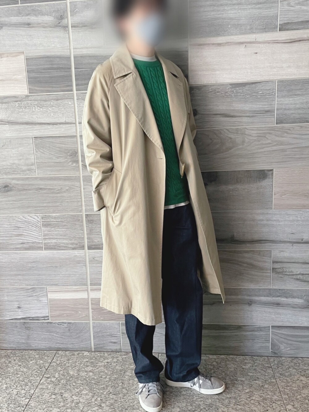 ベージュ系のトレンチコート、グリーン系のニット/セーター、ブルー系のデニムパンツを着用したメンズの冬コーディネートの2枚目の写真