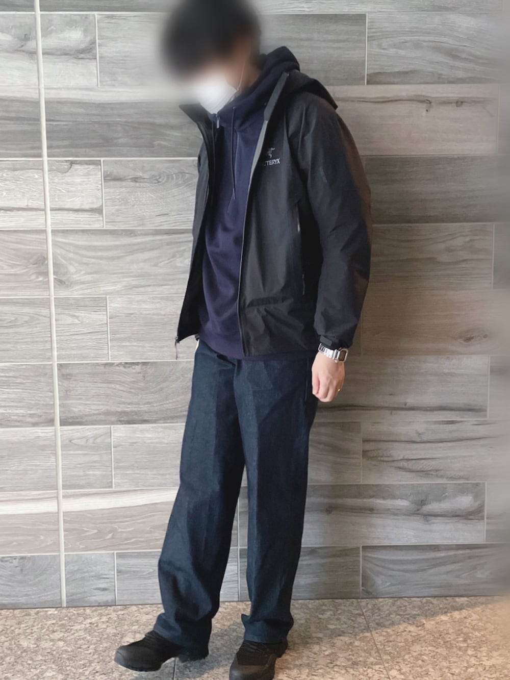 ブラック系のマウンテンパーカー、ブルー系のパーカー、ブルー系のデニムパンツを着用したメンズの春コーディネートの2枚目の写真