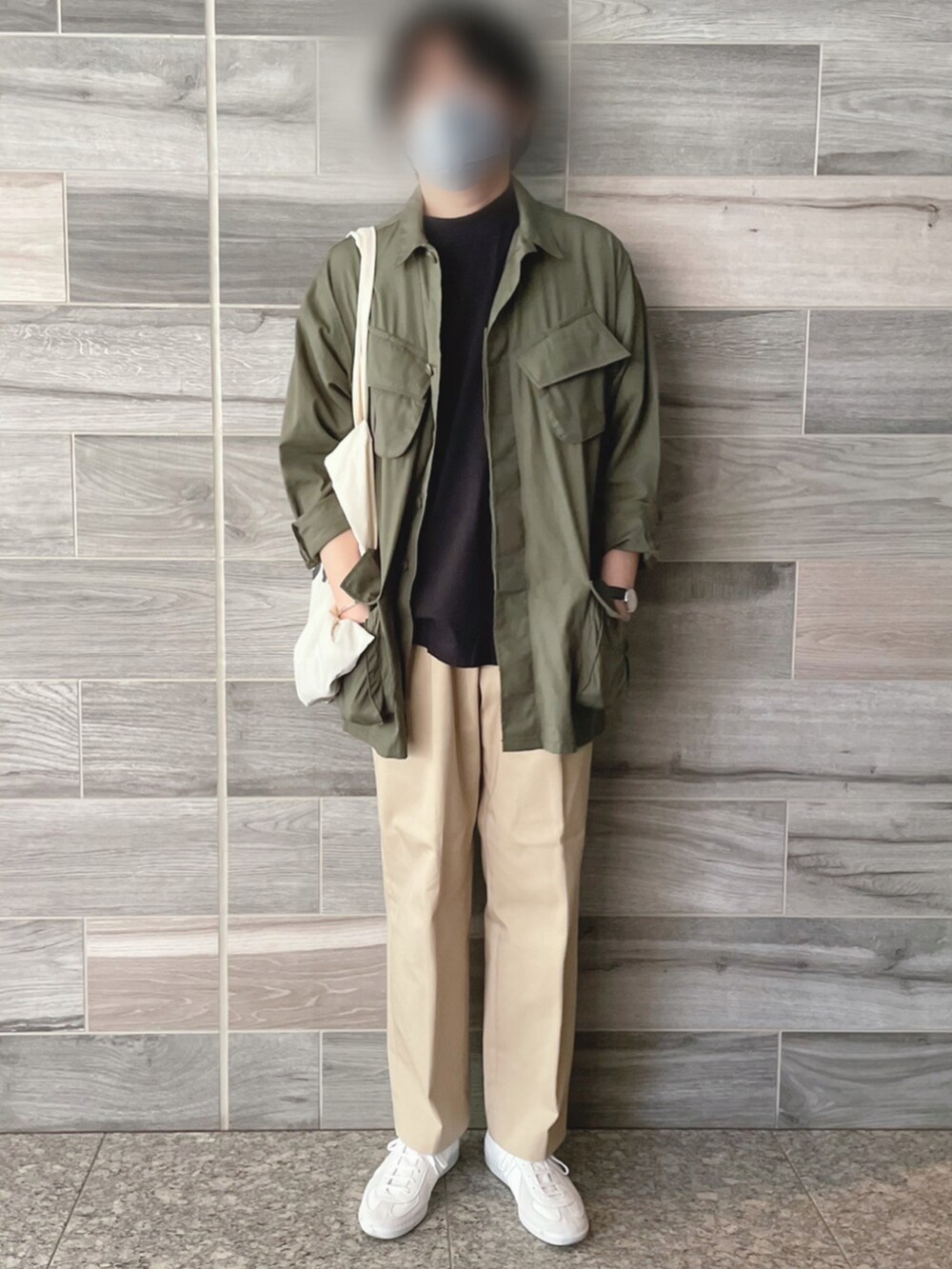 グリーン系のミリタリージャケット、ブラック系のTシャツ/カットソー、ベージュ系のチノパンツを着用したメンズの春コーディネートの4枚目の写真