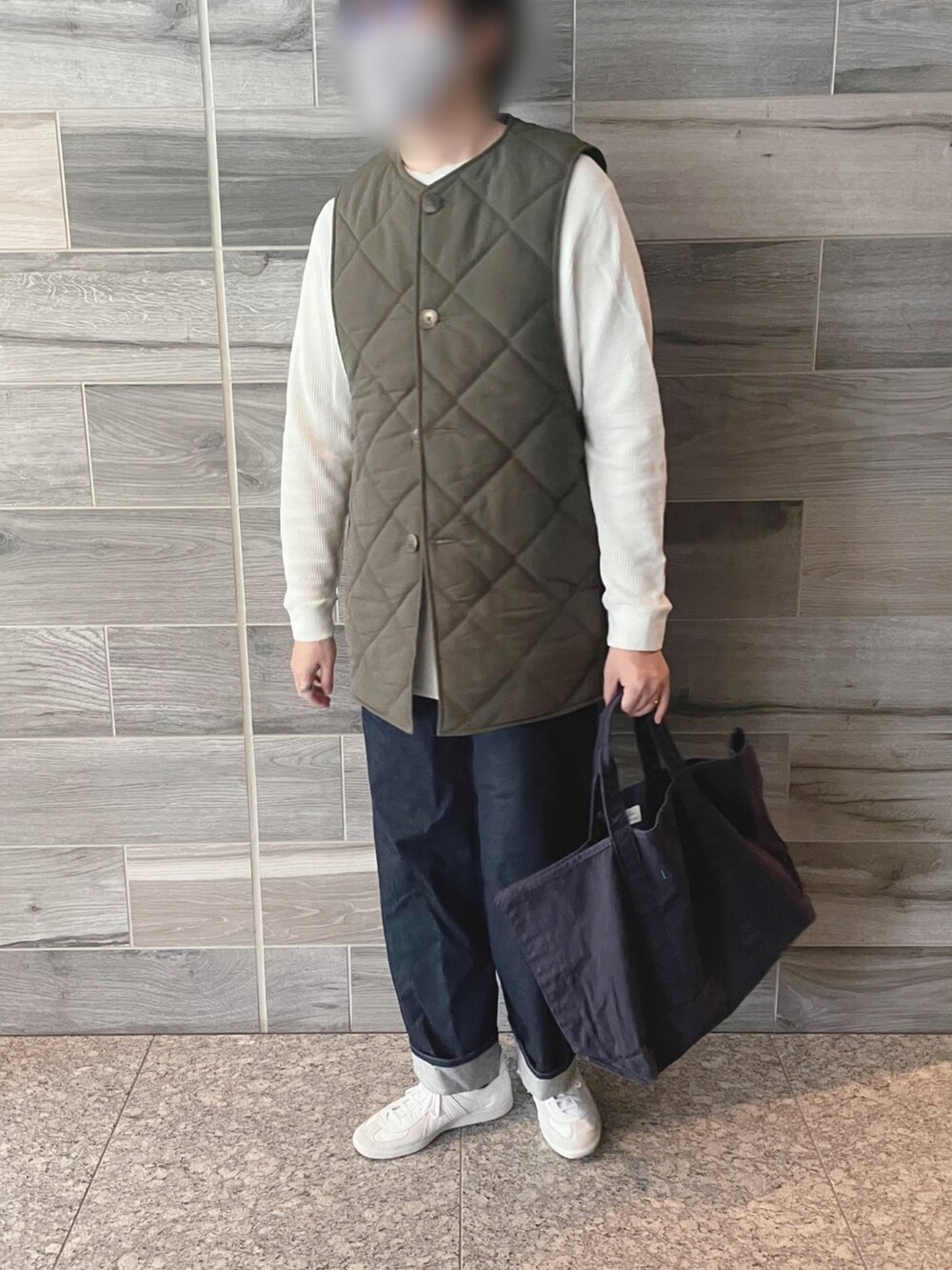 グリーン系のダウンベスト、ホワイト系のTシャツ/カットソー、ブルー系のデニムパンツを着用したメンズの冬コーディネートの2枚目の写真