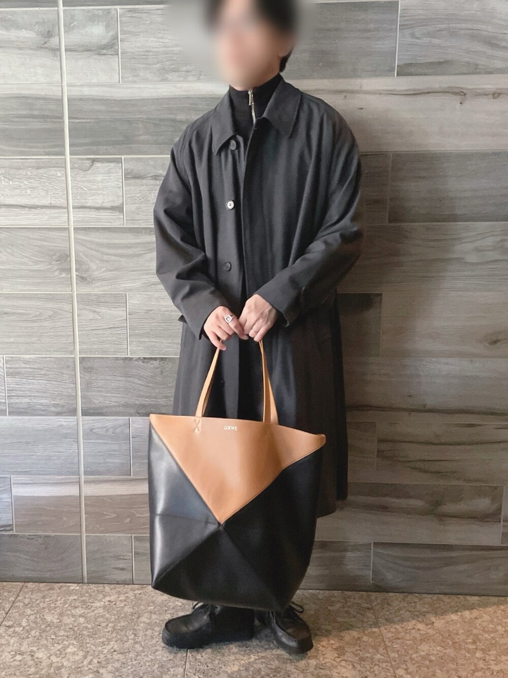 グレー系のステンカラーコート、ブラック系のニット/セーター、ブラック系のスラックスを着用したメンズの冬コーディネートの3枚目の写真