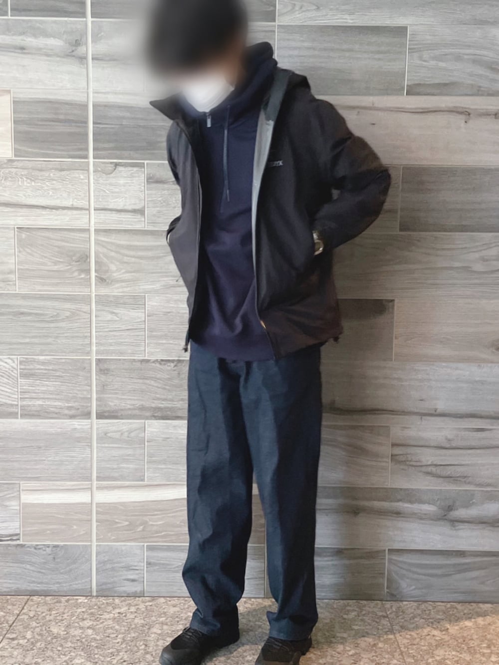 ブラック系のマウンテンパーカー、ブルー系のパーカー、ブルー系のデニムパンツを着用したメンズの春コーディネートの3枚目の写真