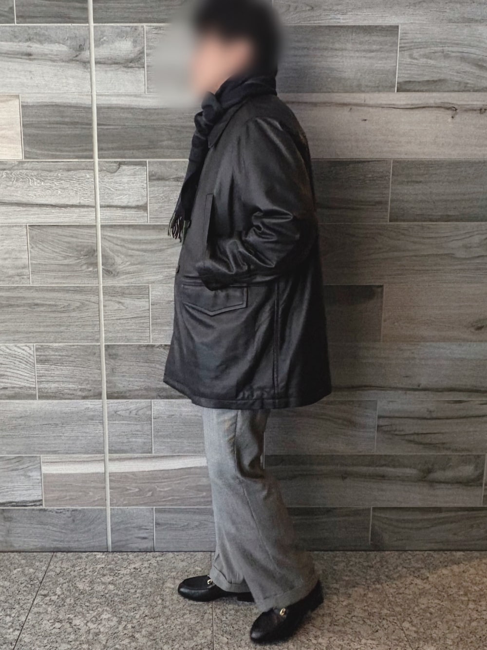 ブラック系のピーコート、グレー系のスラックス、ブラック系のブーツを着用したメンズの冬コーディネートの2枚目の写真