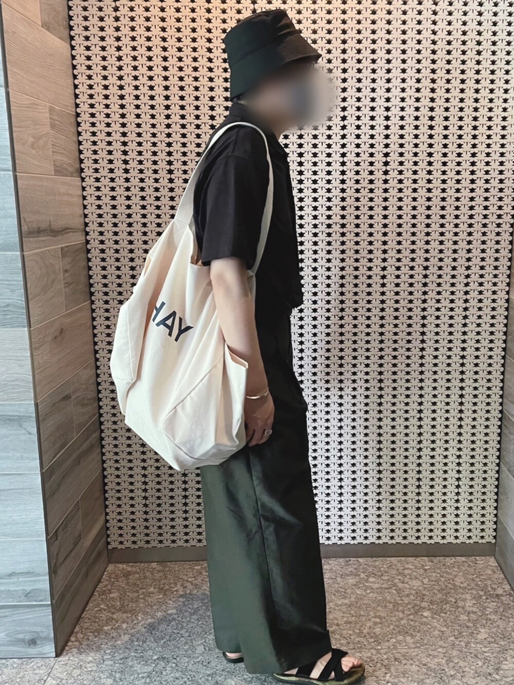 ブラック系のポロシャツ、グリーン系のその他パンツ、ホワイト系のトートバッグを着用したメンズの夏コーディネートの2枚目の写真