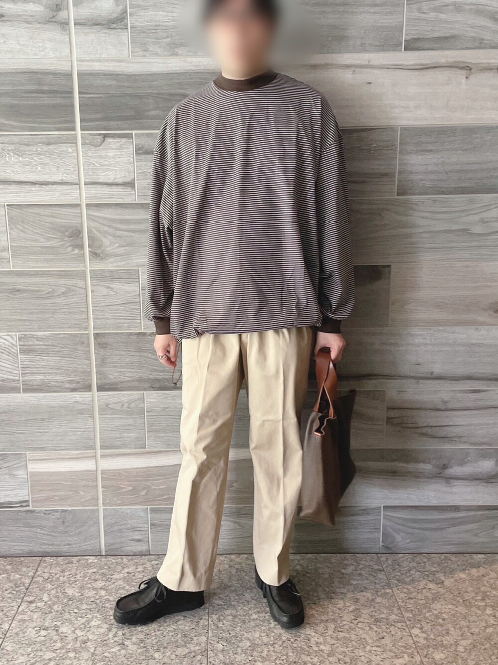 ブラック系のTシャツ/カットソー、ベージュ系のチノパンツ、ブラウン系のトートバッグを着用したメンズの秋コーディネートの3枚目の写真