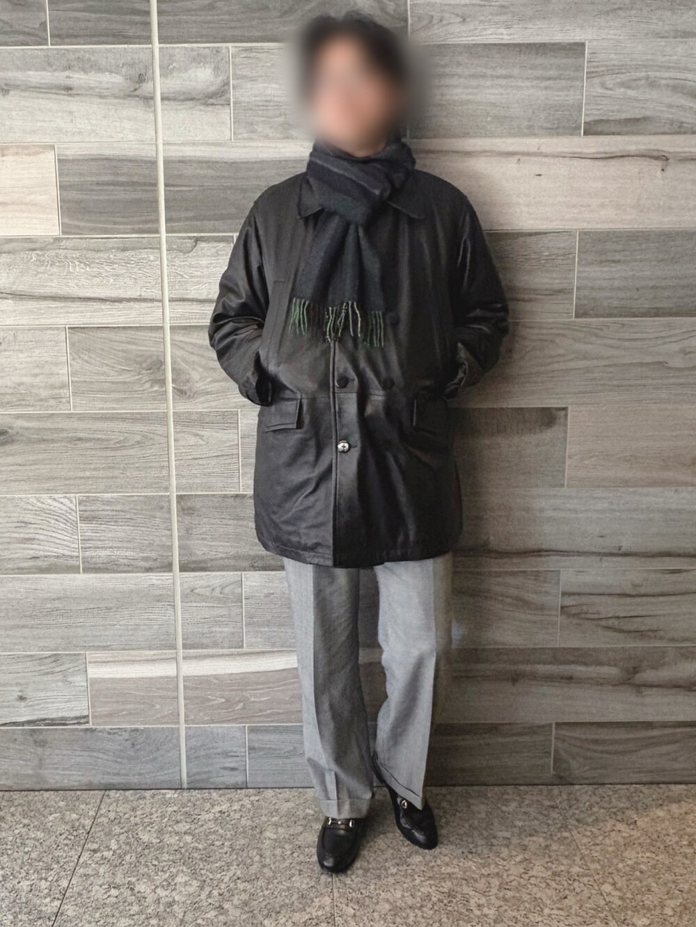 ブラック系のピーコート、グレー系のスラックス、ブラック系のブーツを着用したメンズの冬コーディネートの3枚目の写真