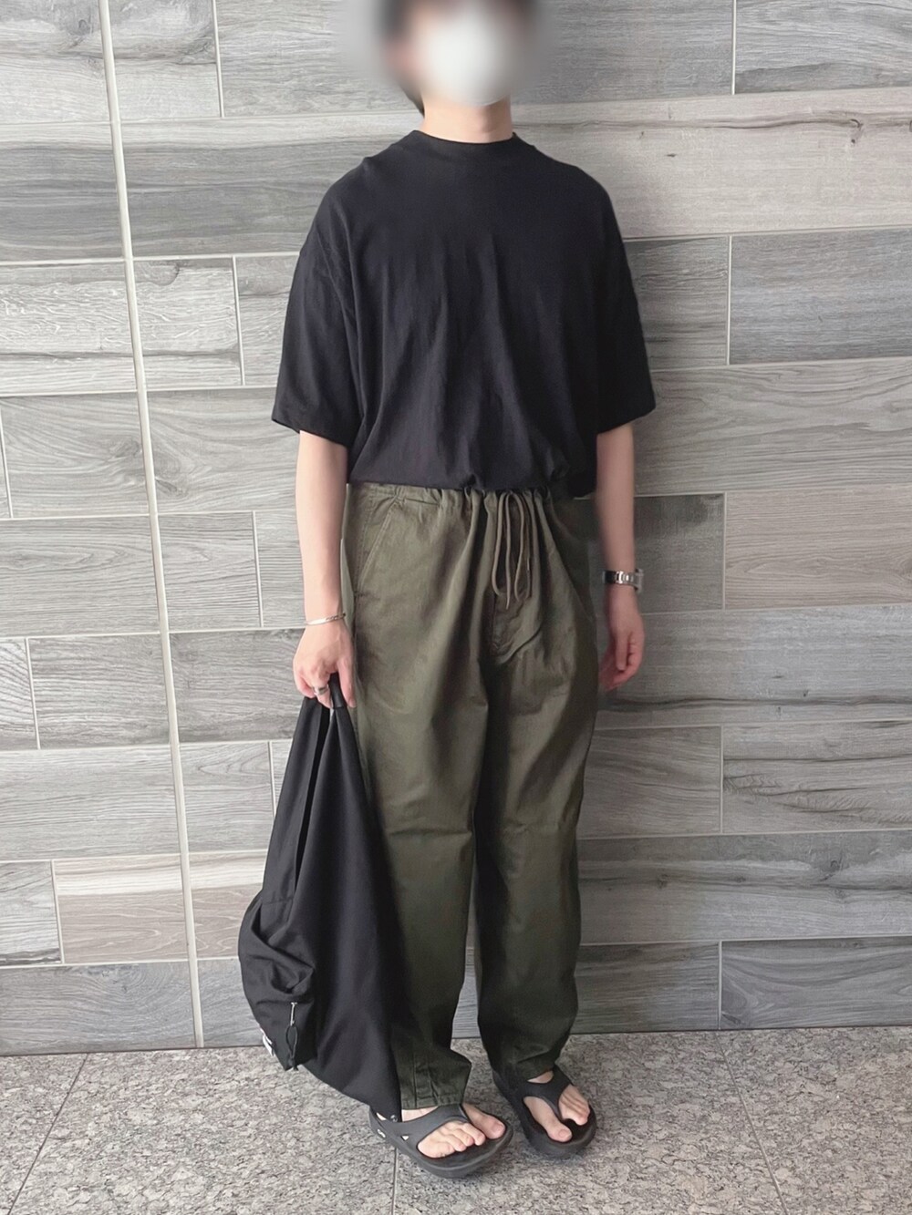 ブラック系のTシャツ/カットソー、グリーン系のパンツ、ブラック系のトートバッグを着用したメンズの秋コーディネートの3枚目の写真