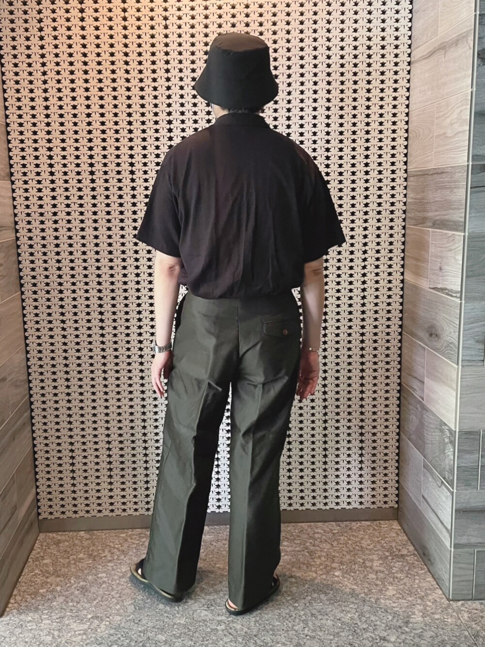 ブラック系のポロシャツ、グリーン系のその他パンツ、ホワイト系のトートバッグを着用したメンズの夏コーディネートの4枚目の写真