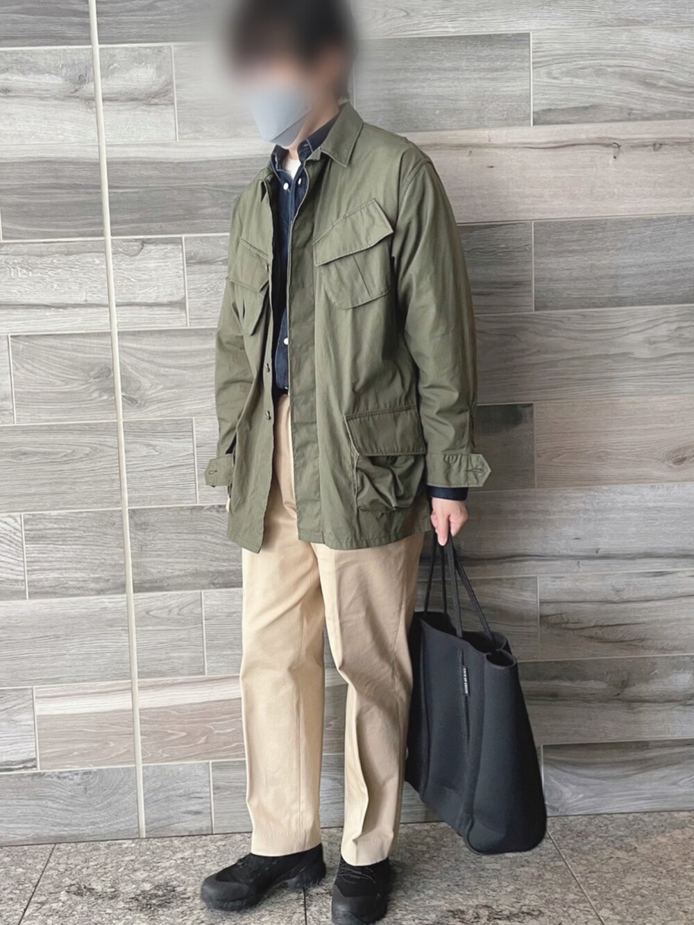 グリーン系のミリタリージャケット、ブルー系のシャツ/ブラウス、ベージュ系のチノパンツを着用したメンズの春コーディネートの2枚目の写真