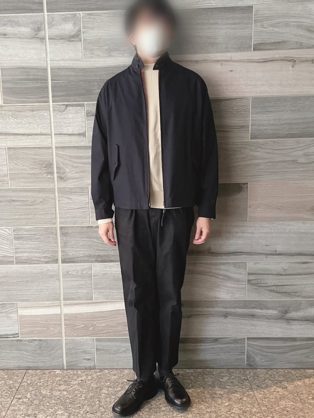 ブルー系のブルゾン、ホワイト系のニット/セーター、ブラック系のスラックスを着用したメンズの春コーディネートの2枚目の写真