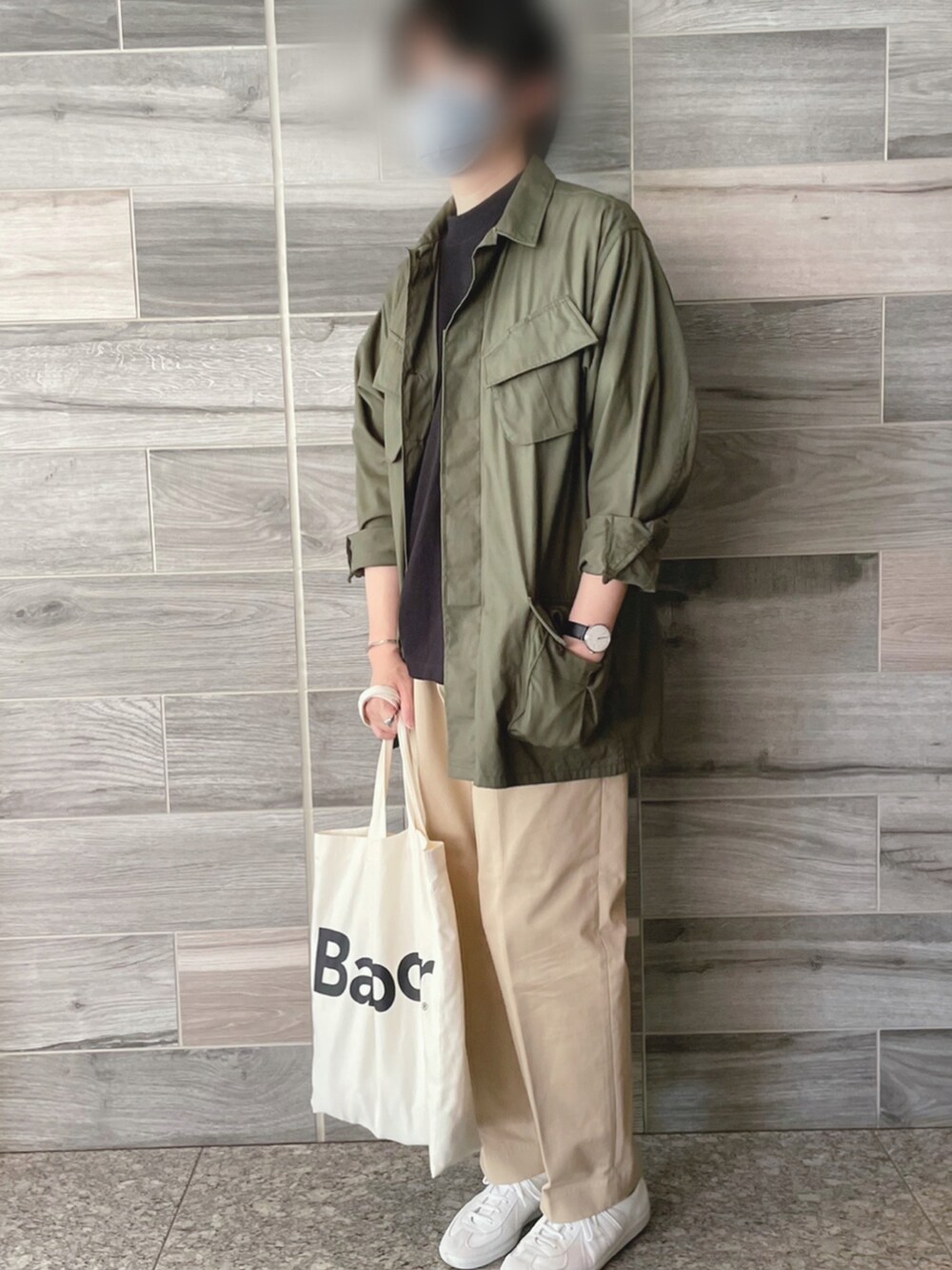 グリーン系のミリタリージャケット、ブラック系のTシャツ/カットソー、ベージュ系のチノパンツを着用したメンズの春コーディネートの3枚目の写真