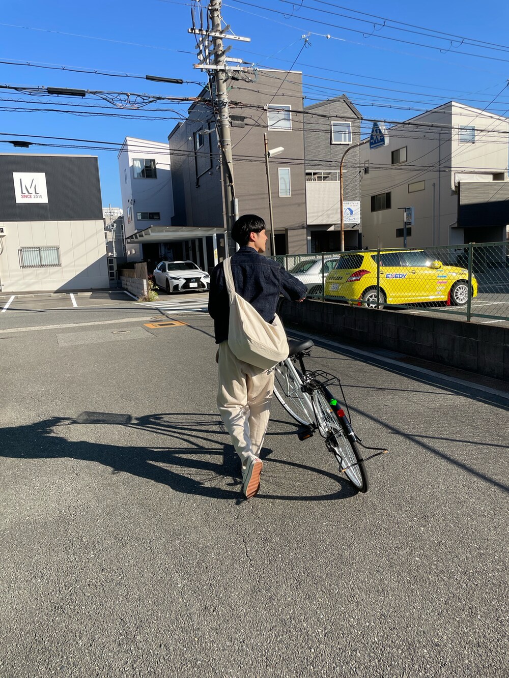 ブルー系のデニムジャケット、ホワイト系のショルダーバッグを着用したメンズの秋コーディネートの2枚目の写真