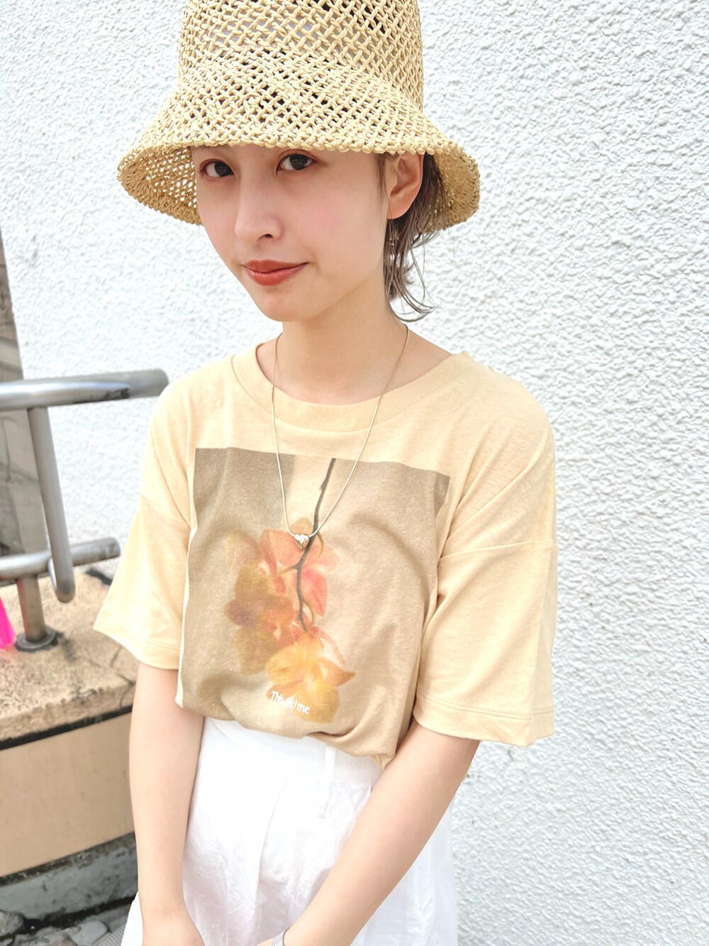 イエロー系のTシャツ/カットソー、ホワイト系のスカート、ベージュ系のハットを着用したレディースの春コーディネートの2枚目の写真