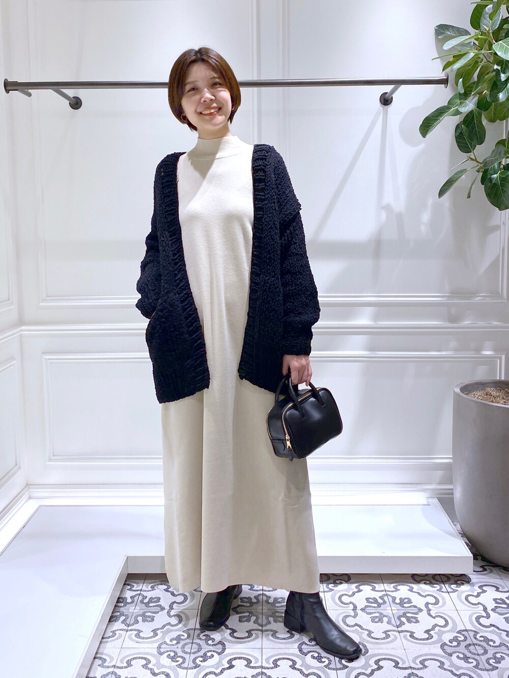ベージュ系のワンピース、ブラック系のニット/セーター、ブラック系のブーツを着用したレディースの冬コーディネートの2枚目の写真