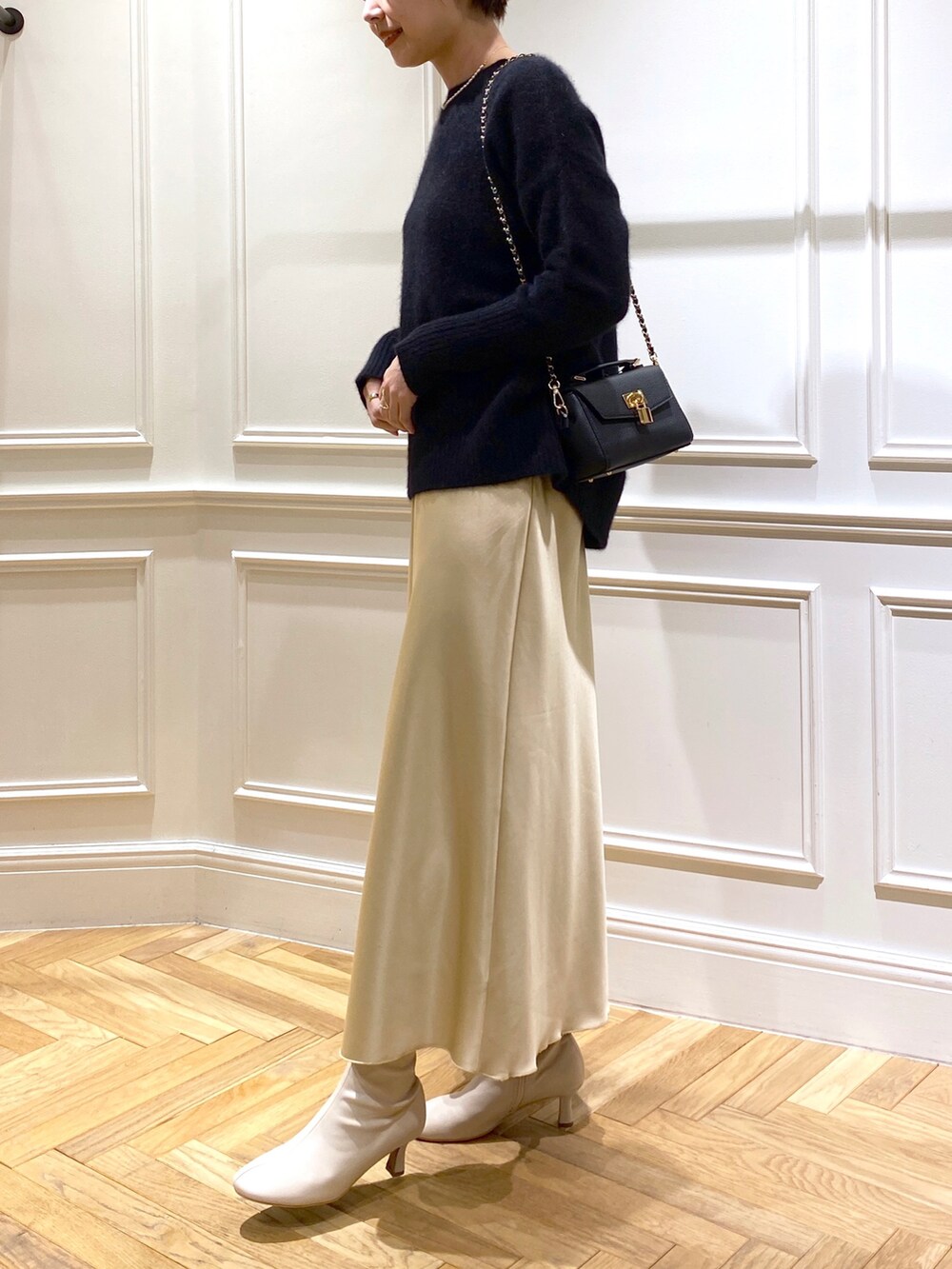 ブラック系のニット/セーター、イエロー系のスカート、ベージュ系のブーツを着用したレディースの秋コーディネートの3枚目の写真