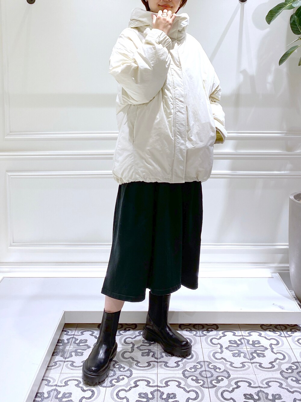 グリーン系のワンピース、ホワイト系のダウンジャケット/コート、ブラック系のブーツを着用したレディースの冬コーディネートの3枚目の写真