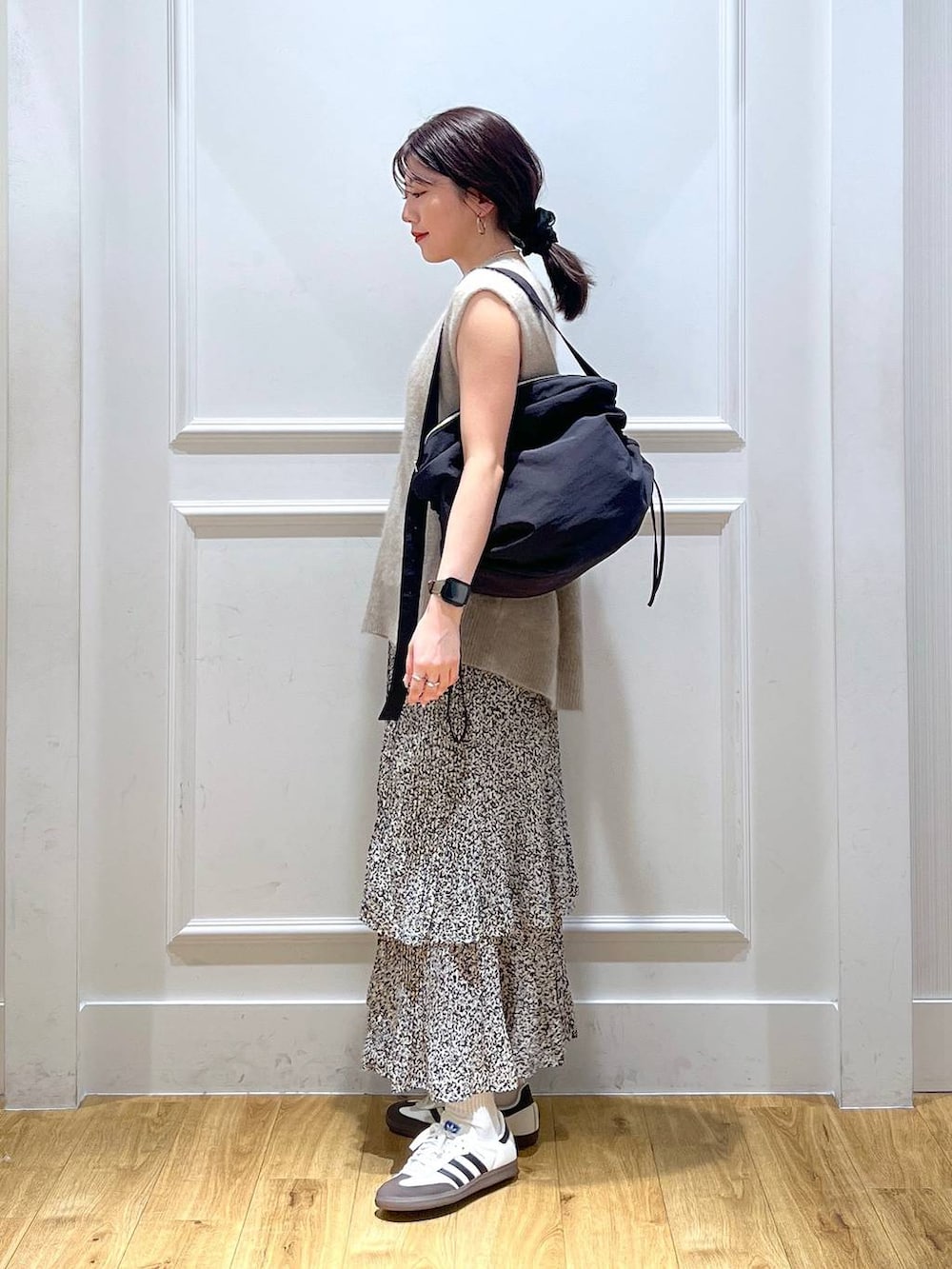 ブラック系のショルダーバッグ、ベージュ系のスカート、ベージュ系のベストを着用したレディースの秋コーディネートの2枚目の写真