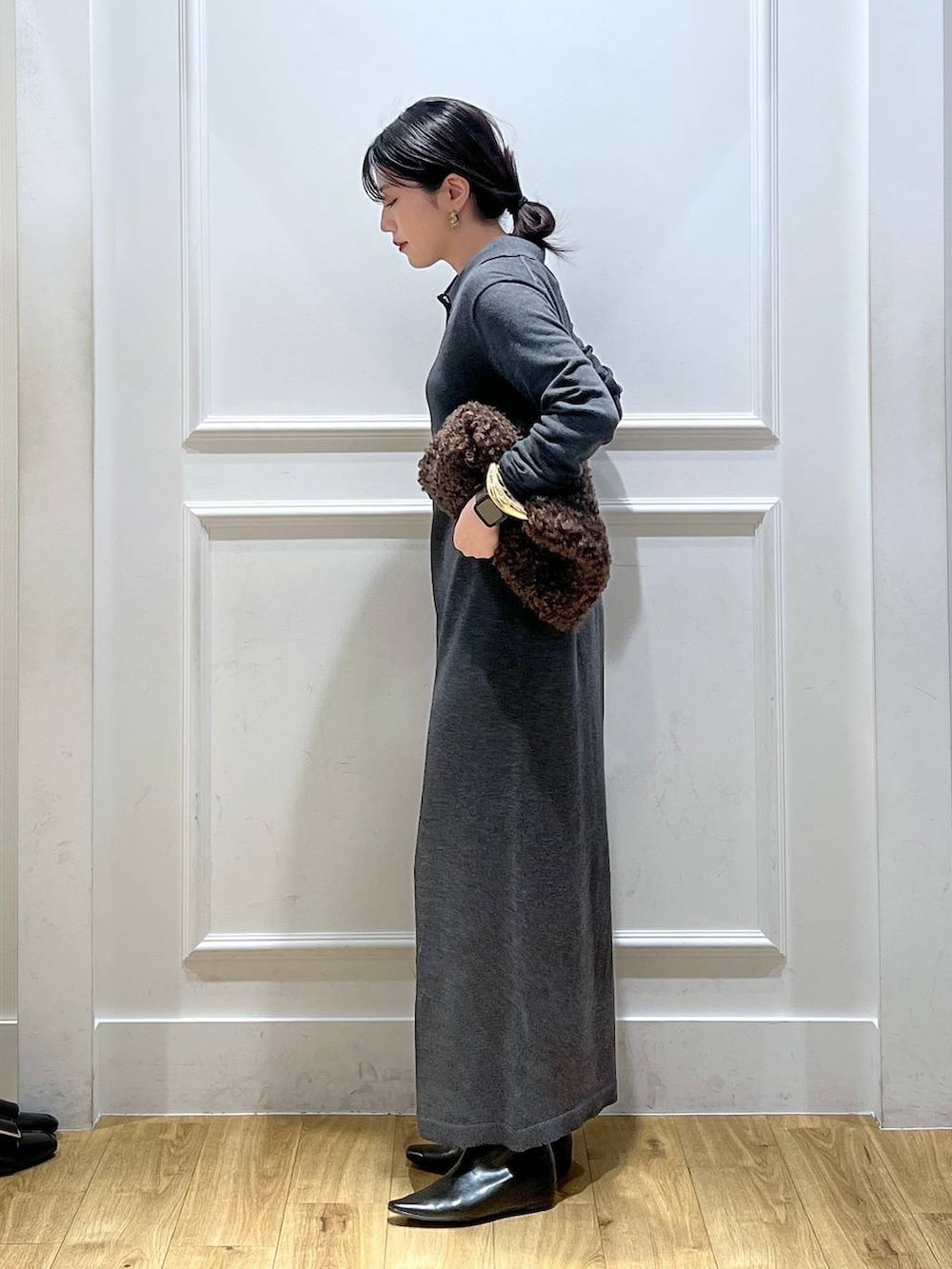 グレー系のワンピース、ブラウン系のハンドバッグを着用したレディースの冬コーディネートの2枚目の写真