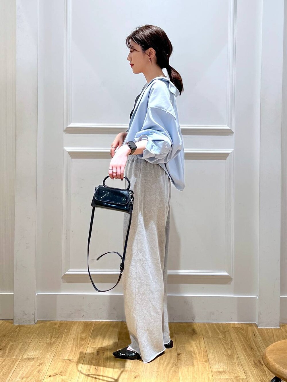 ブルー系のシャツ/ブラウス、グレー系のスウェットパンツ、ブラック系のショルダーバッグを着用したレディースの秋コーディネートの2枚目の写真