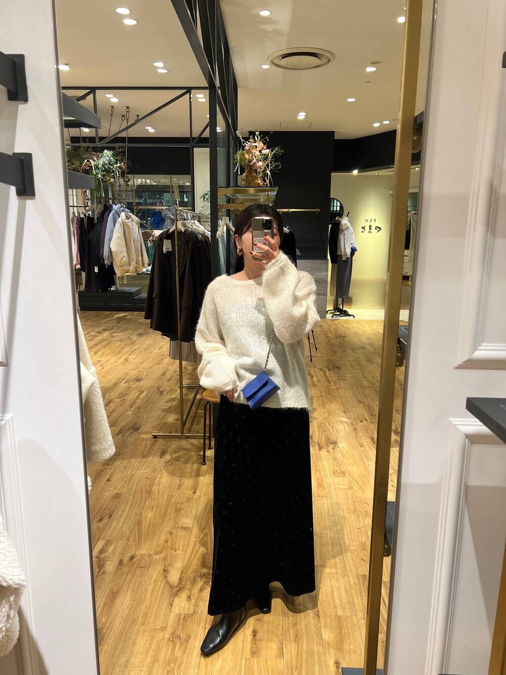 ホワイト系のニット/セーター、ブルー系のショルダーバッグ、ブラック系のスカートを着用したレディースの冬コーディネートの3枚目の写真