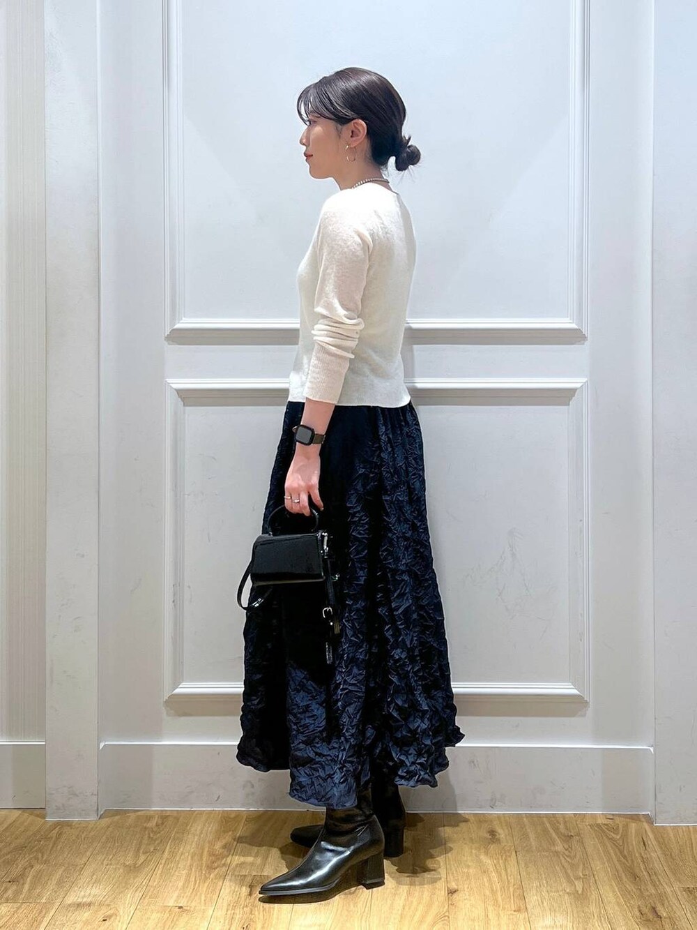ブラック系のショルダーバッグ、ホワイト系のカーディガン/ボレロ、ブルー系のスカートを着用したレディースの秋コーディネートの2枚目の写真