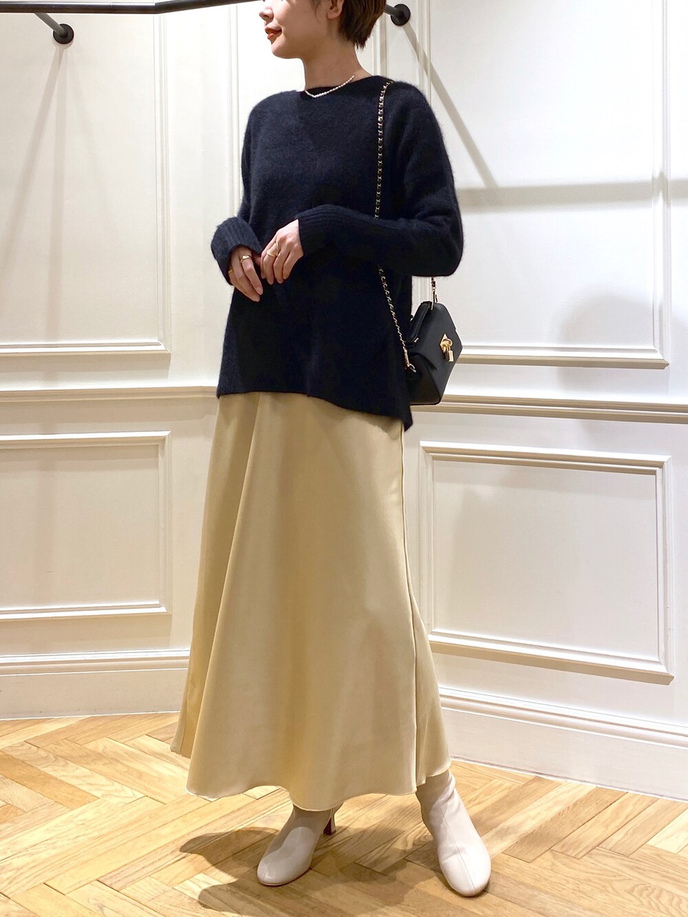 ブラック系のニット/セーター、イエロー系のスカート、ベージュ系のブーツを着用したレディースの秋コーディネートの2枚目の写真