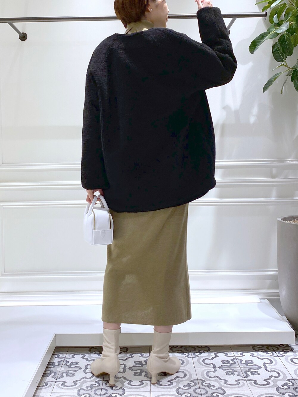 ブラック系のノーカラーコート、グリーン系のワンピース、ベージュ系のブーツを着用したレディースの秋コーディネートの4枚目の写真