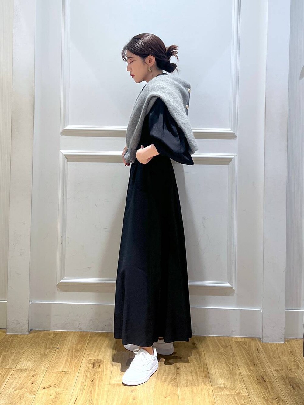 グレー系のカーディガン/ボレロ、ホワイト系のスニーカー、ブラック系のワンピースを着用したレディースの秋コーディネートの2枚目の写真