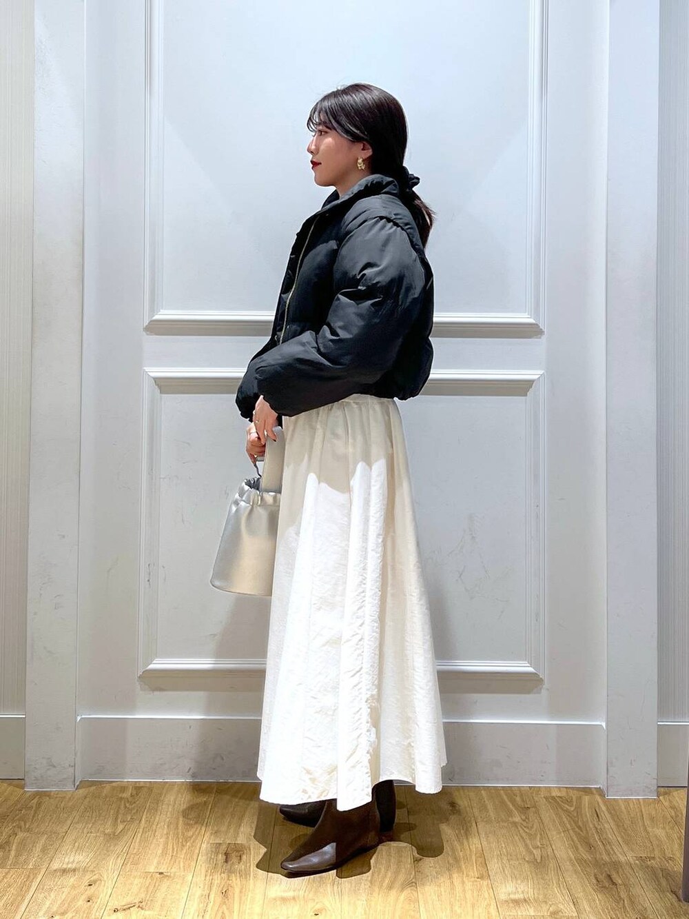 ブラック系のTシャツ/カットソー、ブラウン系のブーツ、シルバー系のショルダーバッグを着用したレディースの冬コーディネートの2枚目の写真