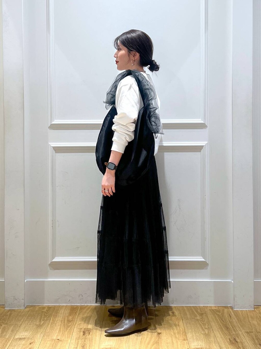 ブラック系のスカート、ブラック系のショルダーバッグ、ブラウン系のブーツを着用したレディースの秋コーディネートの2枚目の写真