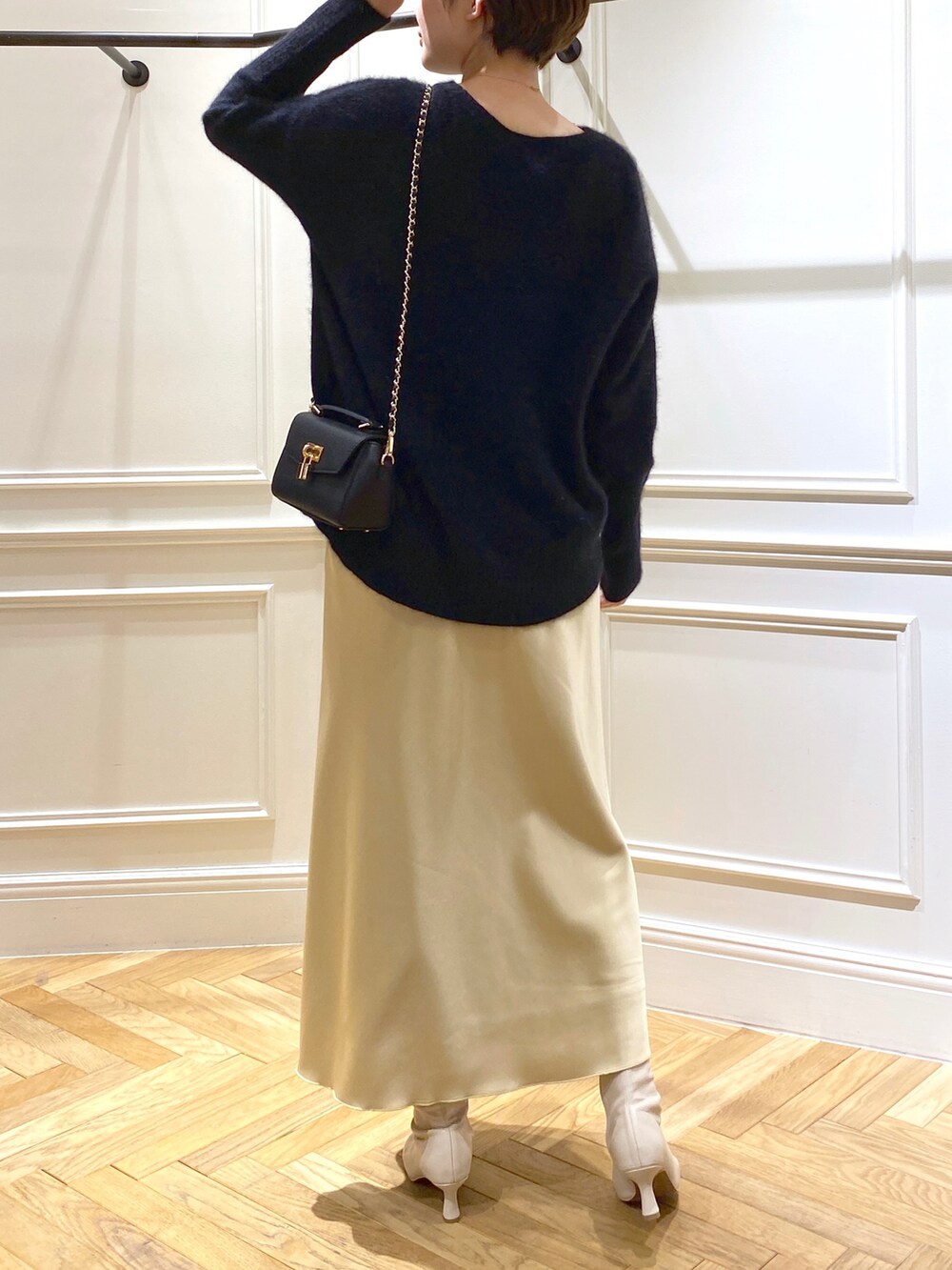 ブラック系のニット/セーター、イエロー系のスカート、ベージュ系のブーツを着用したレディースの秋コーディネートの4枚目の写真