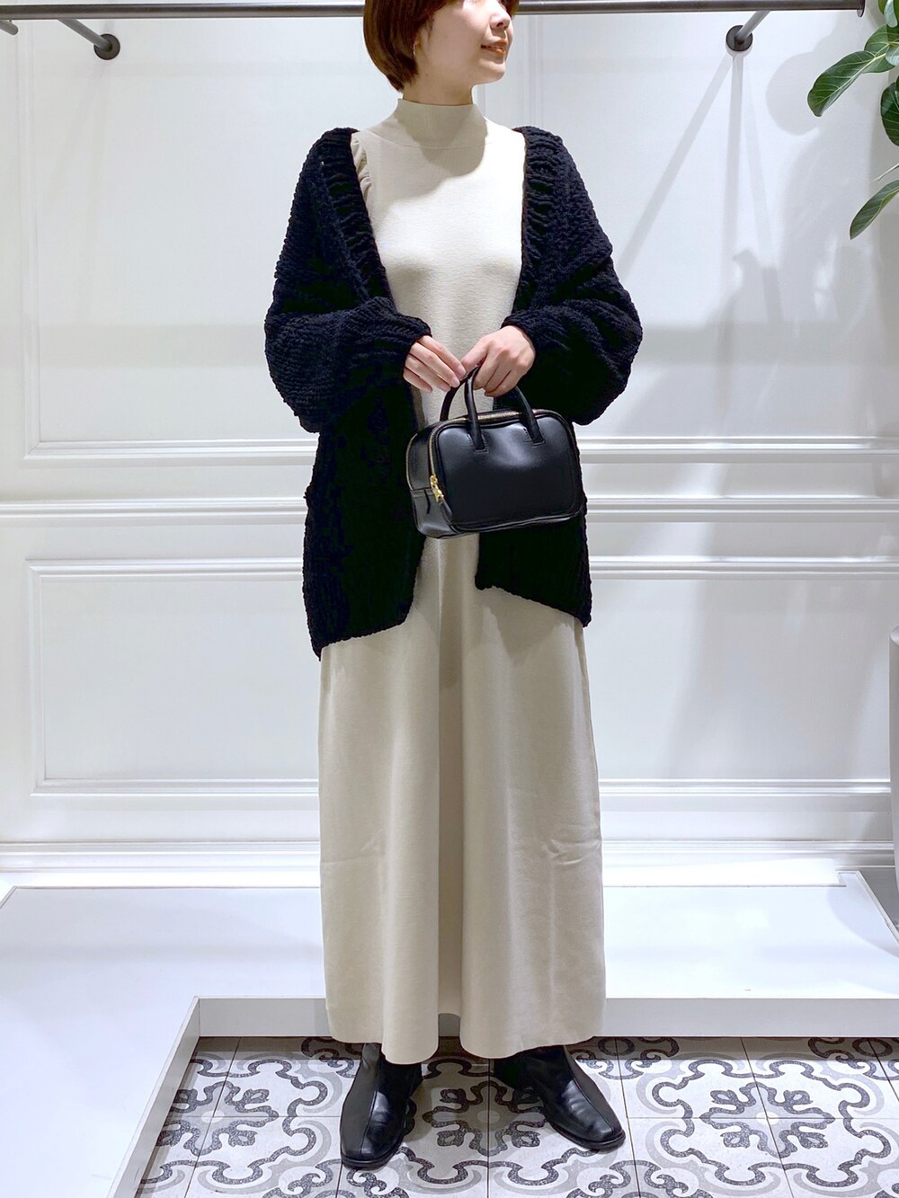 ベージュ系のワンピース、ブラック系のニット/セーター、ブラック系のブーツを着用したレディースの冬コーディネートの3枚目の写真