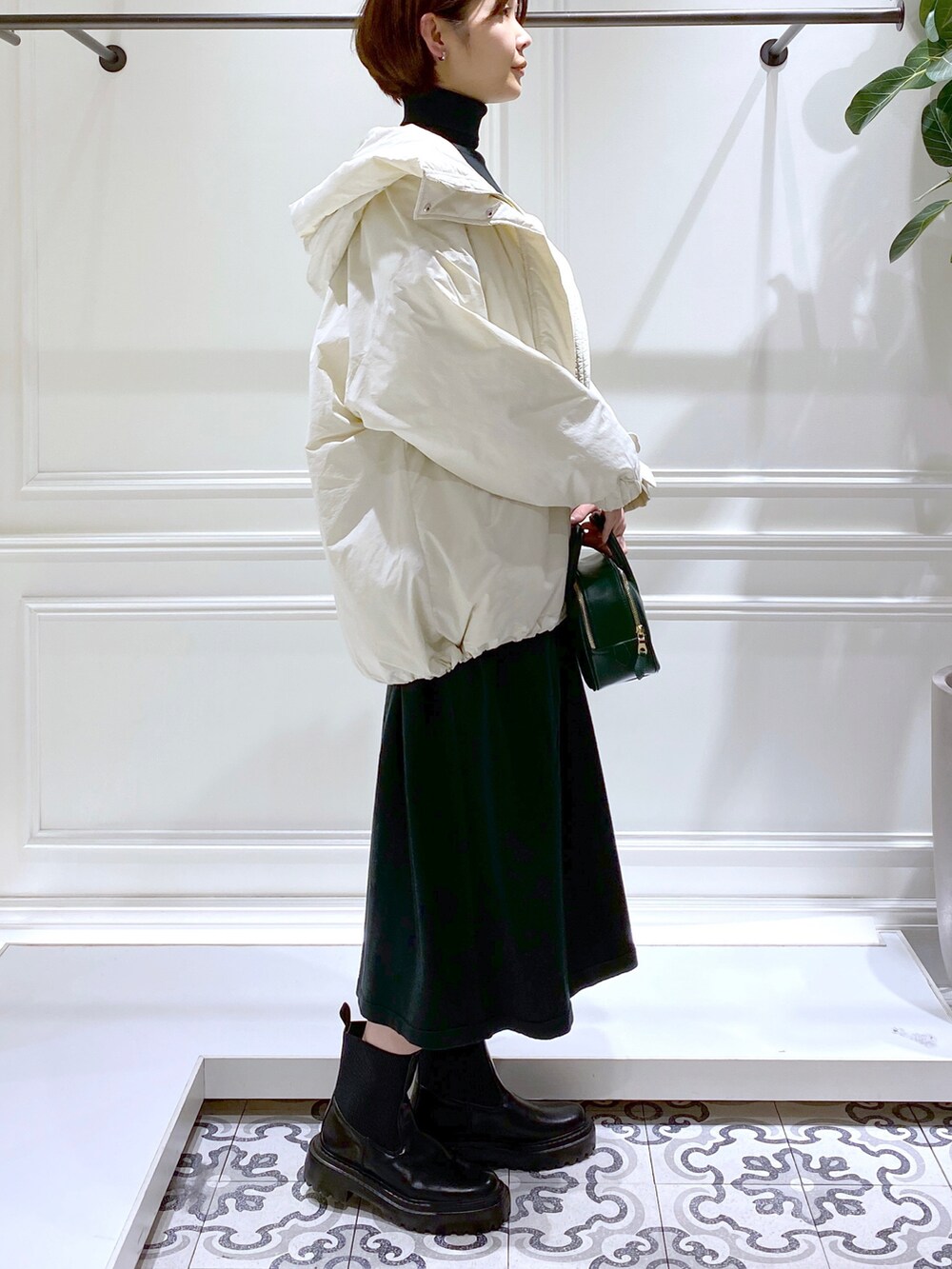グリーン系のワンピース、ホワイト系のダウンジャケット/コート、ブラック系のブーツを着用したレディースの冬コーディネートの4枚目の写真