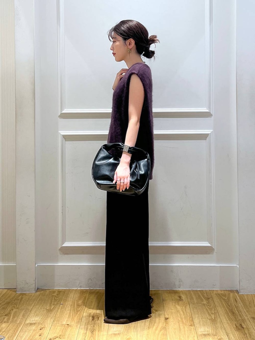 ブラック系のハンドバッグ、ブラック系のスラックス、レッド系のベストを着用したレディースの秋コーディネートの2枚目の写真