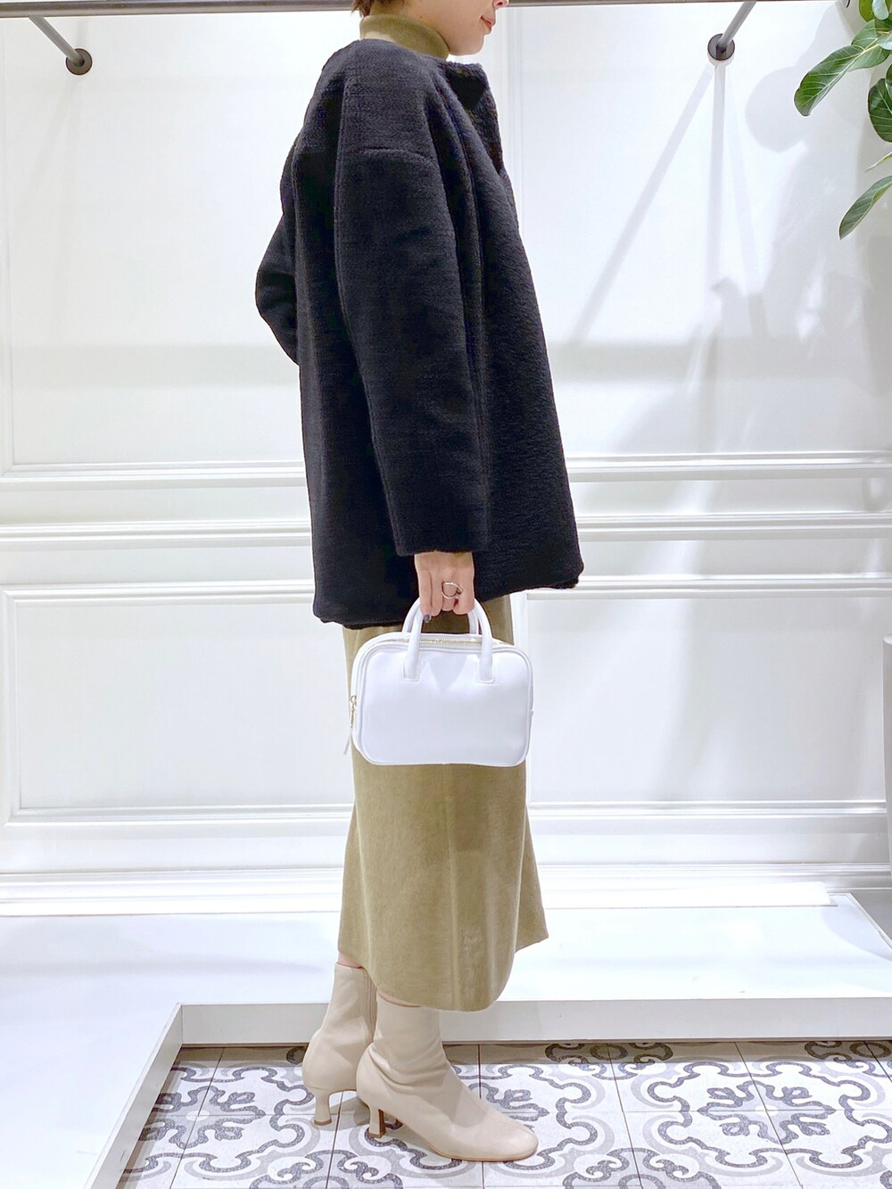 ブラック系のノーカラーコート、グリーン系のワンピース、ベージュ系のブーツを着用したレディースの秋コーディネートの3枚目の写真