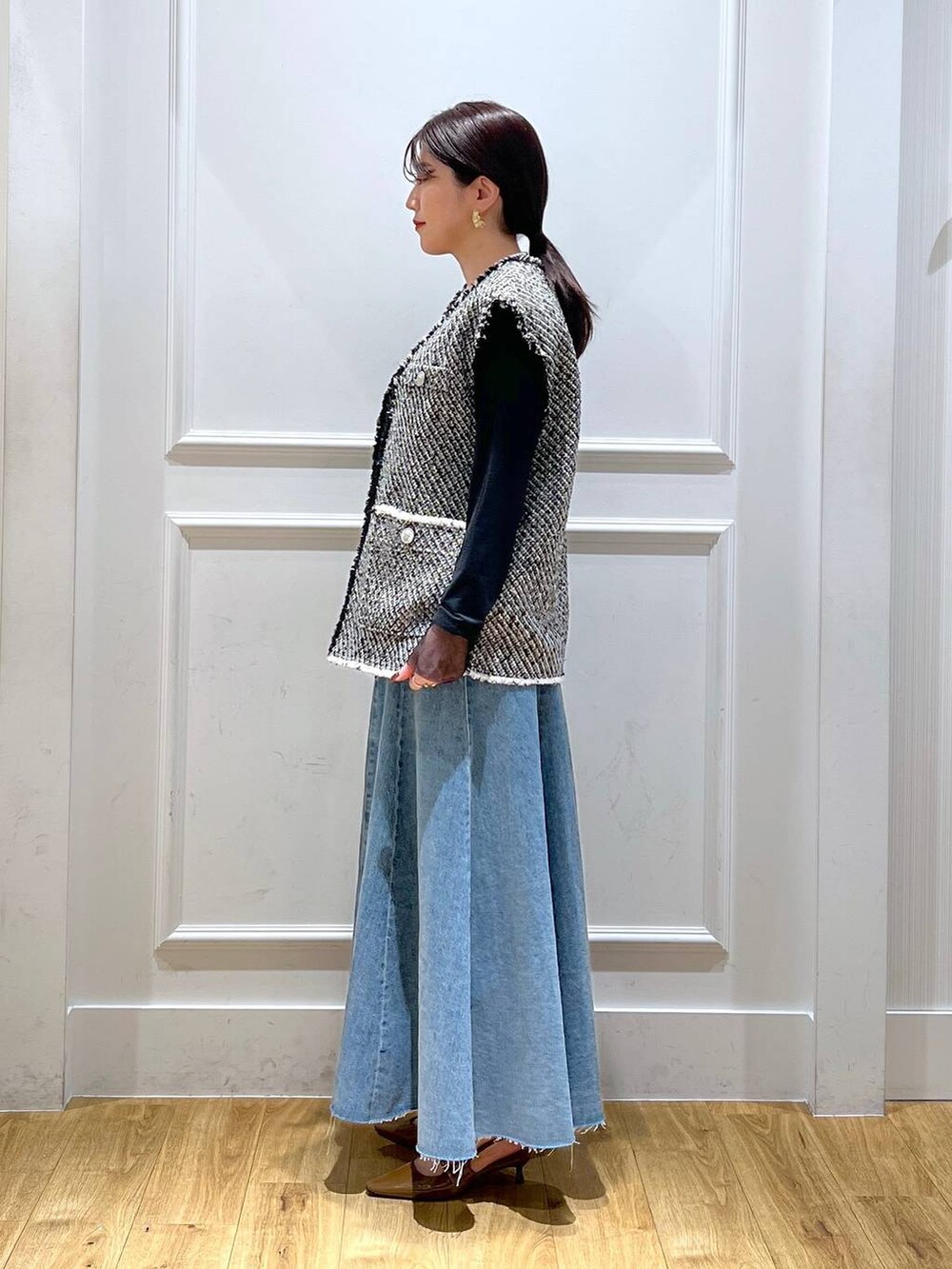 ブルー系のデニムスカート、ブラック系のベスト、ブラック系のTシャツ/カットソーを着用したレディースの春コーディネートの2枚目の写真