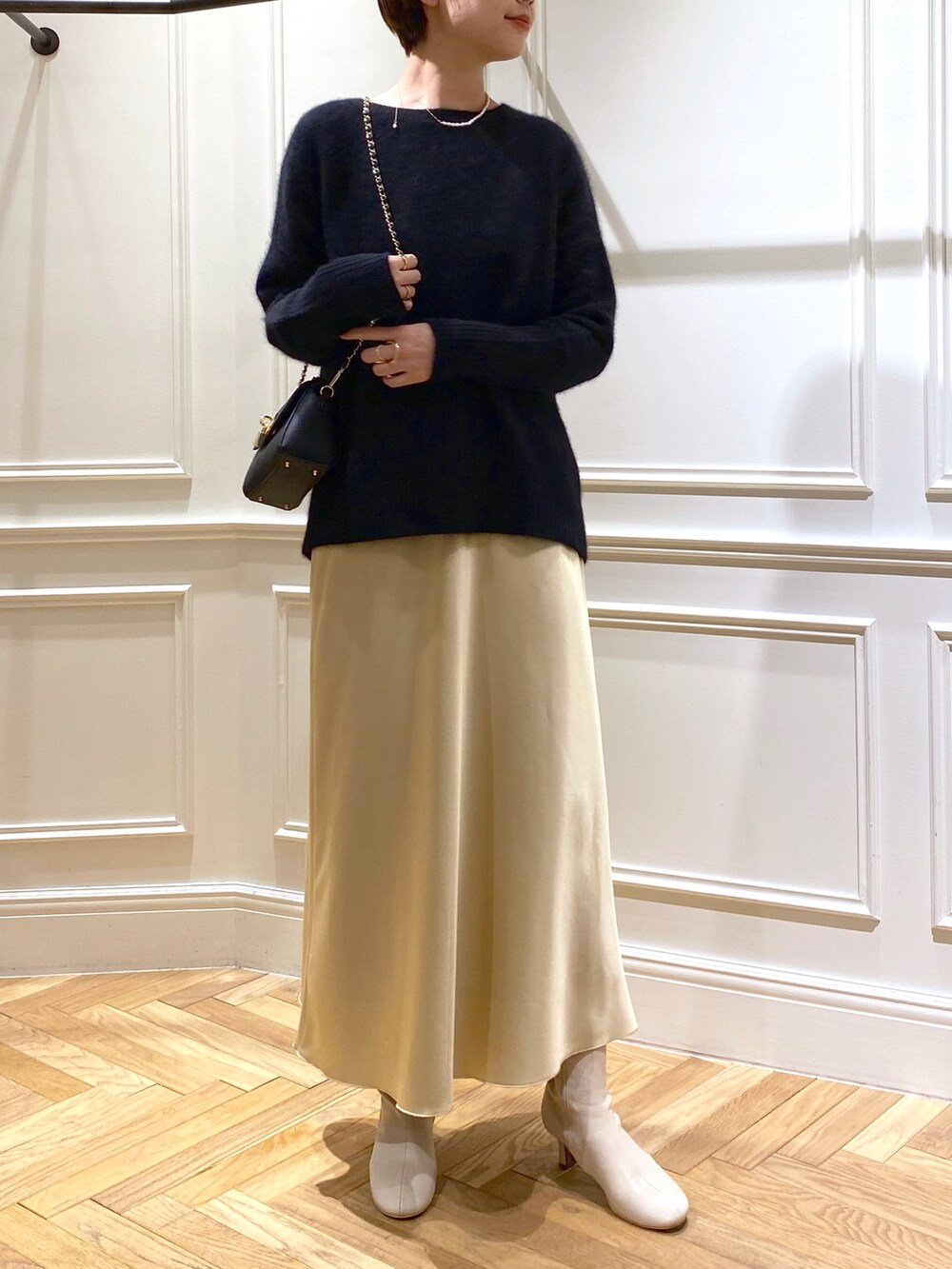 ブラック系のニット/セーター、イエロー系のスカート、ベージュ系のブーツを着用したレディースの秋コーディネートの5枚目の写真