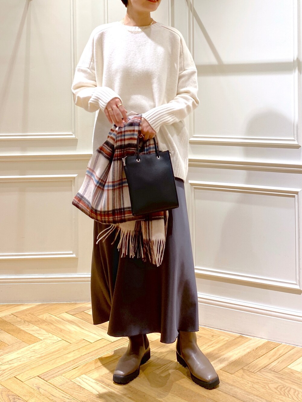 ホワイト系のニット/セーター、グレー系のスカート、ブラック系のショルダーバッグを着用したレディースの秋コーディネートの4枚目の写真
