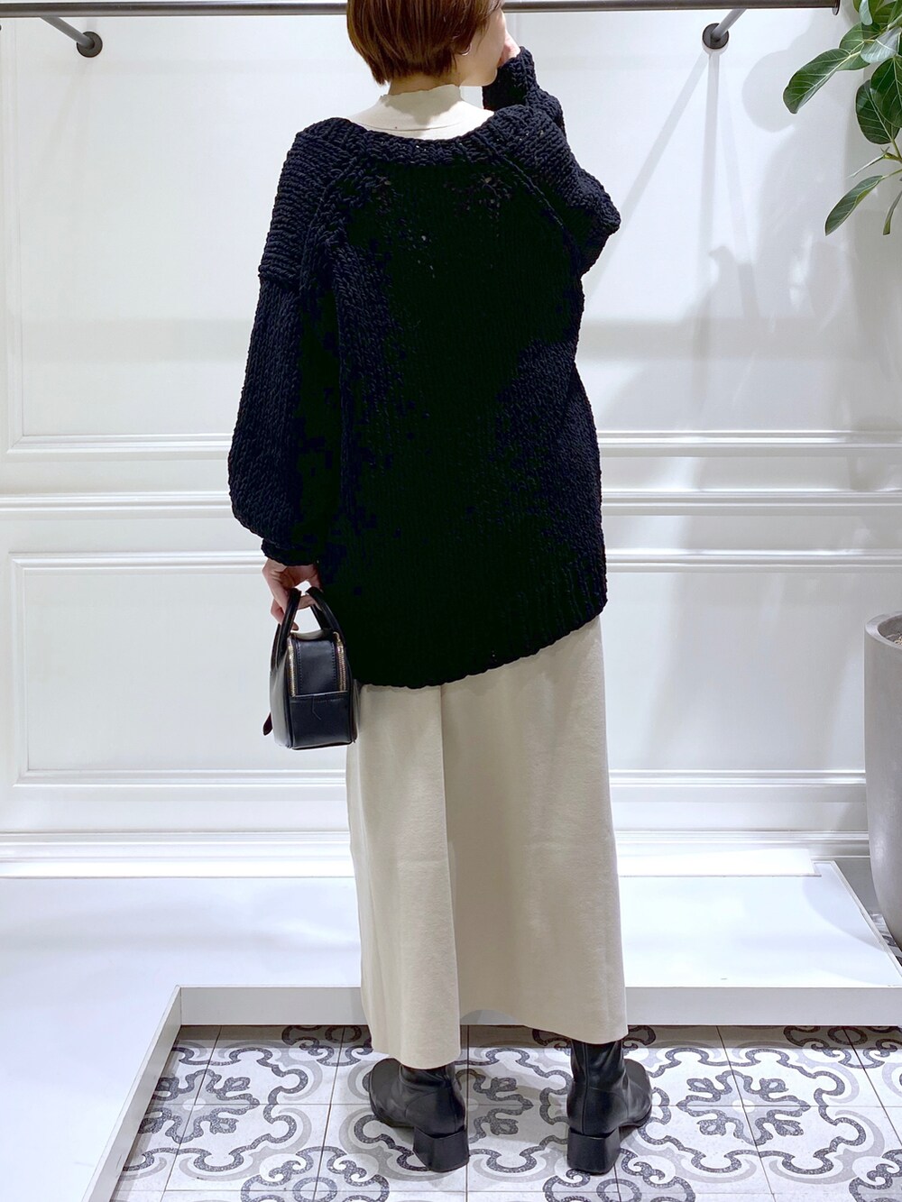 ベージュ系のワンピース、ブラック系のニット/セーター、ブラック系のブーツを着用したレディースの冬コーディネートの5枚目の写真